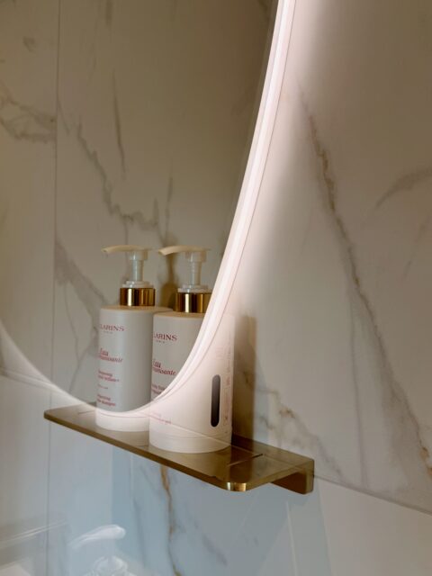 Elegant bathroom with carrara marble details and Clarins products