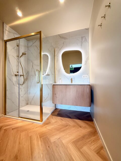 Modern bathroom with marble finishes walk in shower and Clarins Paris soap shampoo and shower gel